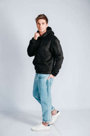 Young muscular man in a light T-shirt and black jeans on a white background. Copy, empty space for text.の写真素材