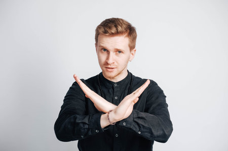 Young man in a black shirt with a smartphone in his hands on a white background. Copy, empty space for text.の写真素材