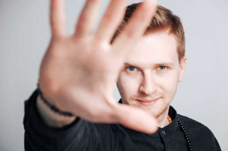 Young man in a black shirt with a smartphone in his hands on a white background. Copy, empty space for text.の写真素材