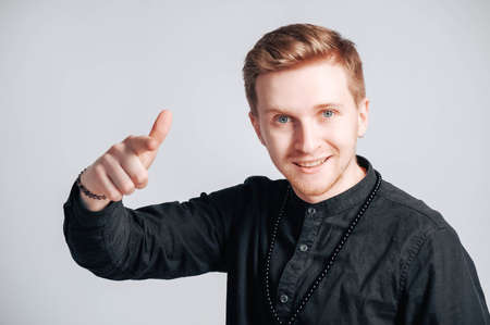Young man in a black shirt with a smartphone in his hands on a white background. Copy, empty space for text.の写真素材
