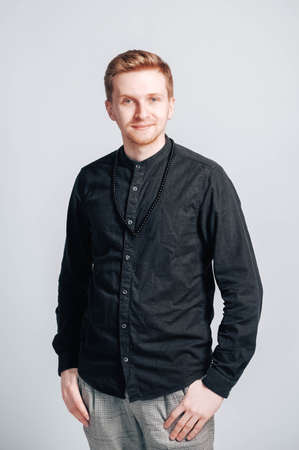 Young man in a black shirt with a smartphone in his hands on a white background. Copy, empty space for text.の写真素材