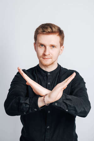 Young man in a black shirt with a smartphone in his hands on a white background. Copy, empty space for text.の写真素材