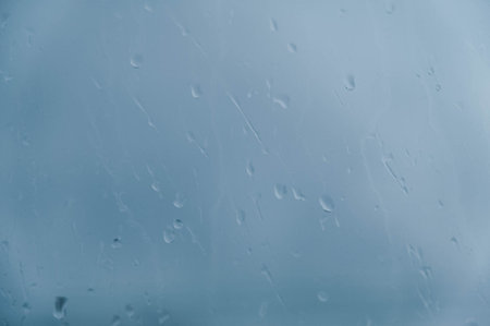 Drops of water run down the glass that is fogged with a blurred background. Copy, empty space for...