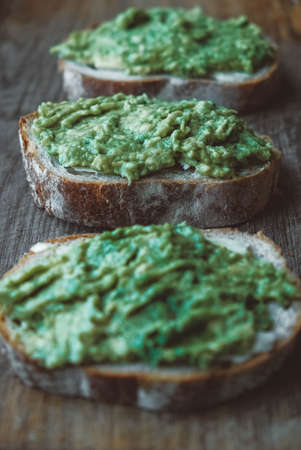 Slices of rye bread with avocado on a wooden background, simple rustic sandwich. Copy, empty space for text.の写真素材
