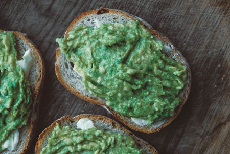 Slices of rye bread with avocado on a wooden background, simple rustic sandwich. Top view. Copy,...