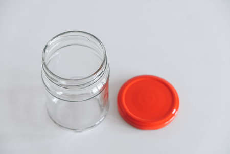 Empty glass jar with red cover on white table background. Top view. Copy, empty space for text.の写真素材