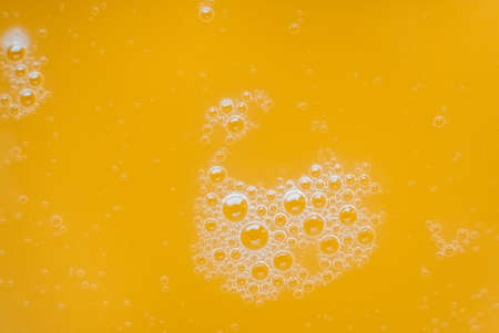Bubbles on the surface of a yellow liquid as a background texture. Top view. Copy, empty space for text.の写真素材
