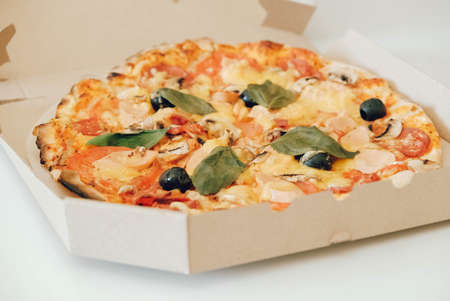 Pizza in a cardboard box on a white table background. Copy, empty space for text.の写真素材