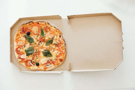 Pizza in a cardboard box on a white table background. Top view. Copy, empty space for text.の写真素材
