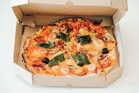 Pizza in a cardboard box on a white table background. Copy, empty space for text.の写真素材