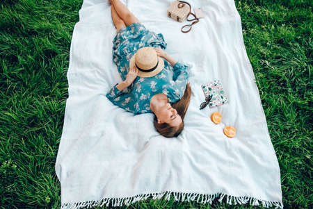 Woman's hand gently touches a yellow flower on a background of green grass. Copy, empty space for text.の写真素材