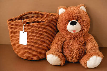 Toy teddy bear with a knitted bag on a brown background. Copy, empty space for text.の写真素材