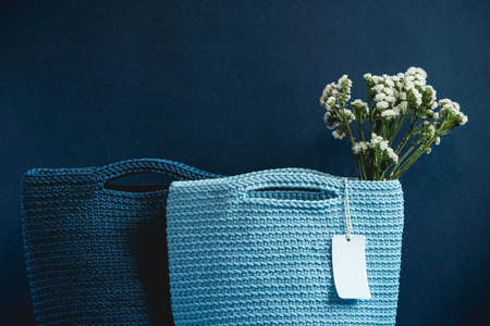 Two blue knitted handmade bag with flowers on a blue background. Copy, empty space for text.の写真素材