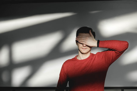 Young man in a red sweater on a white background with shadows from the light. Copy, empty space for text.の写真素材
