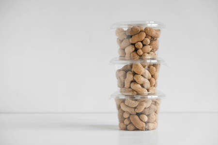 Dry peanuts in a transparent plastic bowls on a white background. Copy, empty space for text.の写真素材