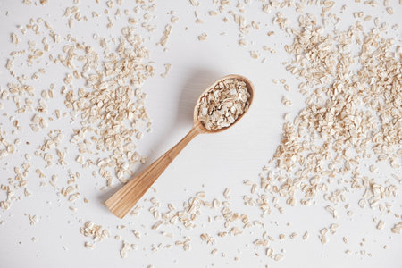 Uncooked oatmeal in a wooden spoon on a white background. Top view. Copy, empty space for text.の写真素材