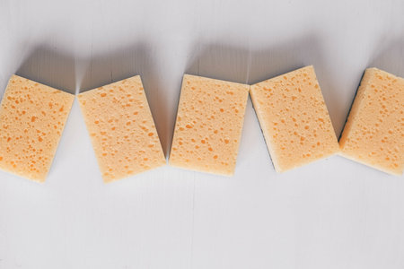 Yellow porous sponges on a white background. Top view. Copy, empty space for text.