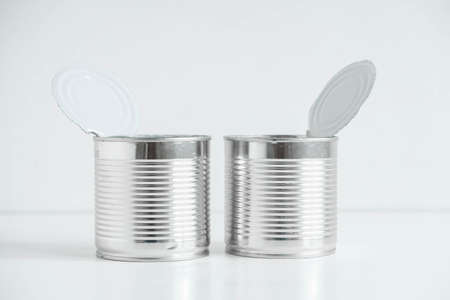 Two open aluminum metal canned food on a white table. Copy, empty space for text.の写真素材