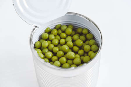 Canned green sweet peas in an open aluminum metal can on a white table. Top view. Copy, empty space for text.の写真素材