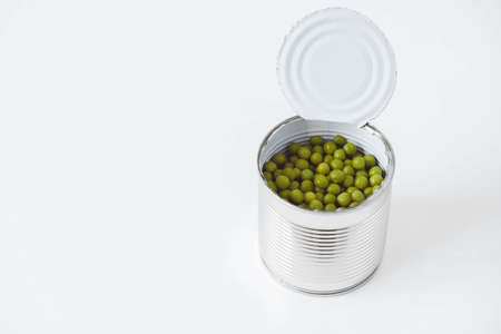Canned green sweet peas in an open aluminum metal can on a white table. Copy, empty space for text.の写真素材