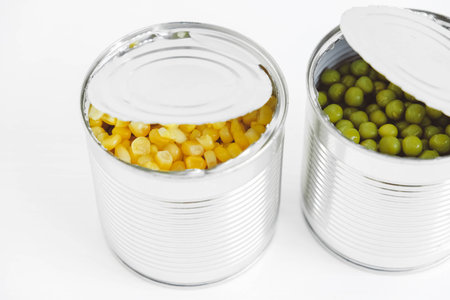 Two open cans with corn and peas on a white background. Copy, empty space for text.の写真素材