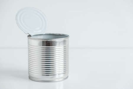 One open aluminum metal canned food on a white table. Copy, empty space for text.の写真素材