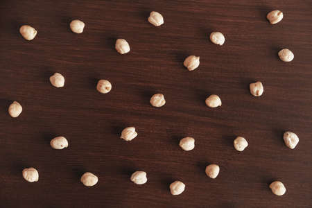 Dry chickpeas scattered on a brown wooden background. Top view. Copy, empty space for text.の写真素材