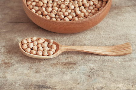 Raw chickpeas in a wooden plate and spoon on an rustic wooden background. Top view. Copy, empty space for text.の写真素材