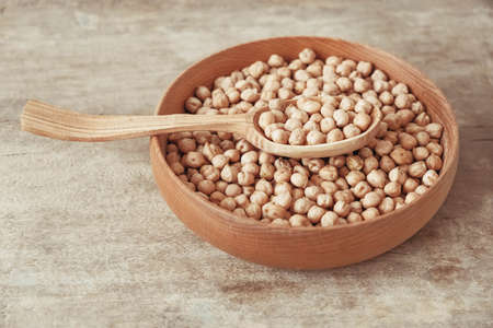 Raw chickpeas in a wooden plate and spoon on an rustic wooden background. Top view. Copy, empty space for text.の写真素材