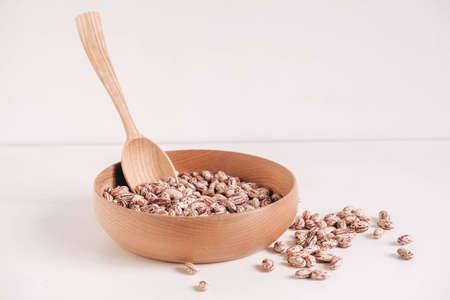 Raw dry beans in a wooden bowl with a spoon on a white background. Copy, empty space for text.の写真素材