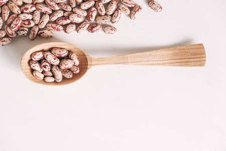 Raw dry beans in a wooden spoon scattered on a white background. Top view. Copy, empty space for text.の写真素材