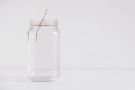 Glass transparent jar on a white table and wall background. Copy, empty space for text.の写真素材