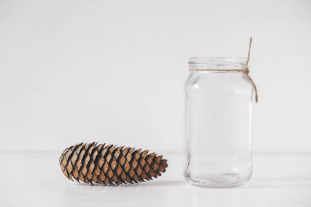 Pine cone and glass jar on a white background. Copy, empty space for text.