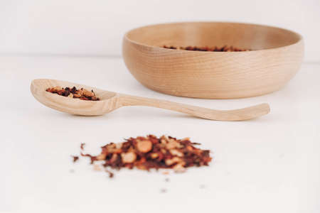 Dry fruit tea in a wooden spoon and a wooden plate on a white background. Top view. Copy, empty space for text.の写真素材