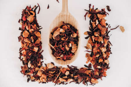 Dry fruit tea in a wooden spoon scattered on a white background. Top view. Copy, empty space for text.の写真素材