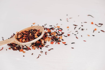Dry fruit tea in a wooden spoon scattered on a white background. Top view. Copy, empty space for...