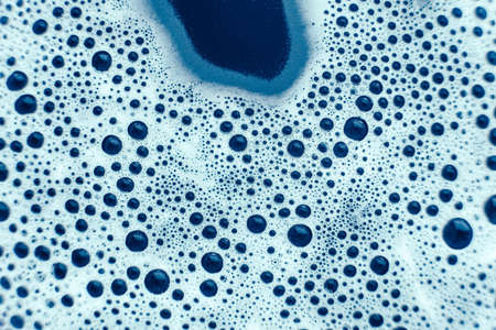Soap bubbles on a background of blue water as a texture. Top view. Copy, empty space for text.の写真素材
