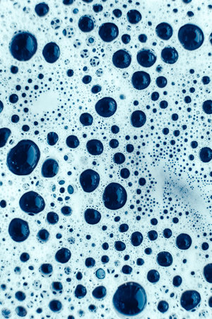 Soap bubbles on a background of blue water as a texture. Top view. Copy, empty space for text.