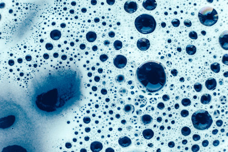 Soap bubbles on a background of blue water as a texture. Top view. Copy, empty space for text.