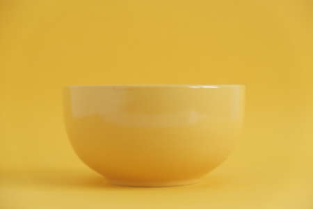Yellow empty ceramic bowl on a yellow background. Copy, empty space for text.の写真素材