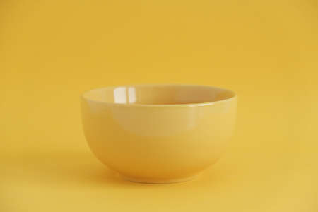 Yellow empty ceramic bowl on a yellow background. Copy, empty space for text.の写真素材