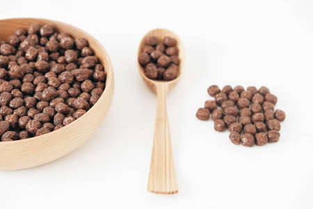 Chocolate corn balls in a wooden bowl and spoon on a white background. Top view. Copy, empty space for text.の写真素材