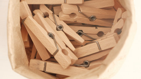 Many wooden clothespins on a white table background. Housework concept.