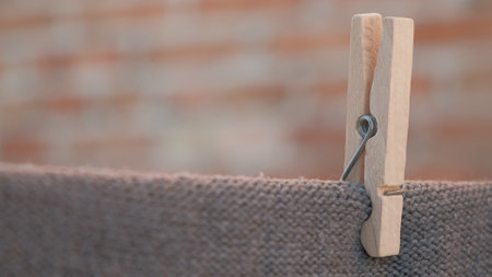 One wooden clothespin holding clothes on a rope. Drying on a wire, gently moved by the wind, housework concept.の写真素材