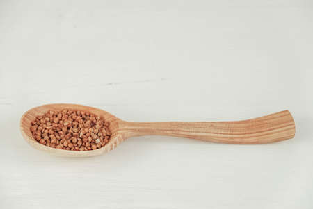 Buckwheat in a wooden spoon on a white background. Copy, empty space for text.の写真素材