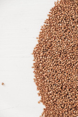 Buckwheat is randomly scattered on a white background. Top view. Copy, empty space for text.