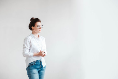 Portrait of a serious beautiful woman in optical glasses and a white shirt on a white background. Copy, empty space for text.の写真素材