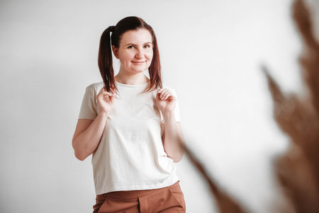 Beautiful woman with pigtails and a funny face wearing a T-shirt on a white background. Copy, empty space.の写真素材