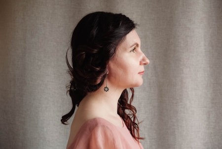 Beautiful brunette woman in a pink dress on a background of linen fabric. Copy, empty space for text.の写真素材