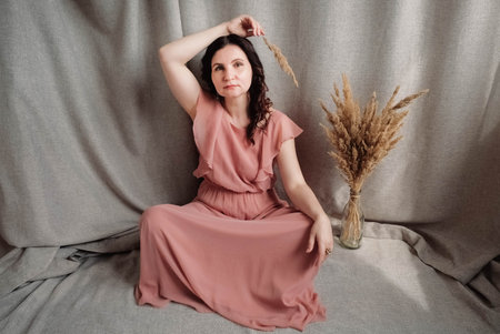 Beautiful brunette woman in a pink dress on a background of linen fabric. Copy, empty space for text.の写真素材
